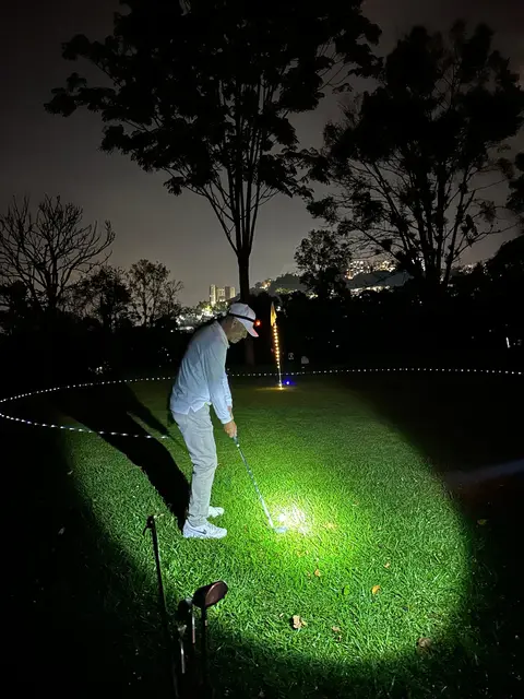 Un jugador golpea de noche, iluminado por una linterna