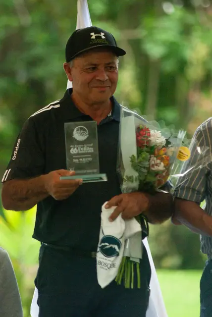 Un socio sonríe con su trofeo y un ramo de flores